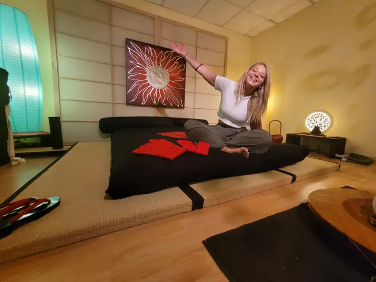 Kit Tatami + Futon naturale, vista angolare, con ragazza sopra che saluta con un sorriso