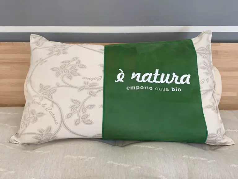 Cuscino bio appoggiato sopra il letto, che mostra la parte esterna del cuscino in lino naturale.